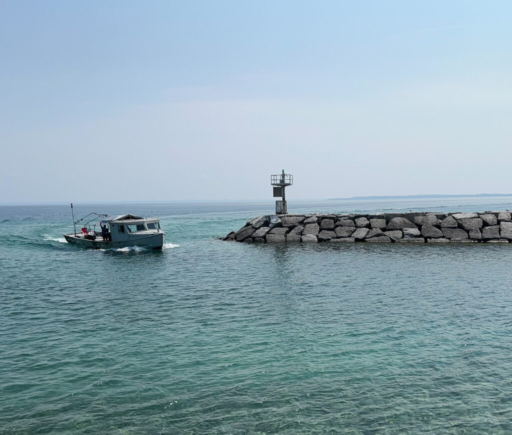 A small boat on water by a marina made of large rocks.