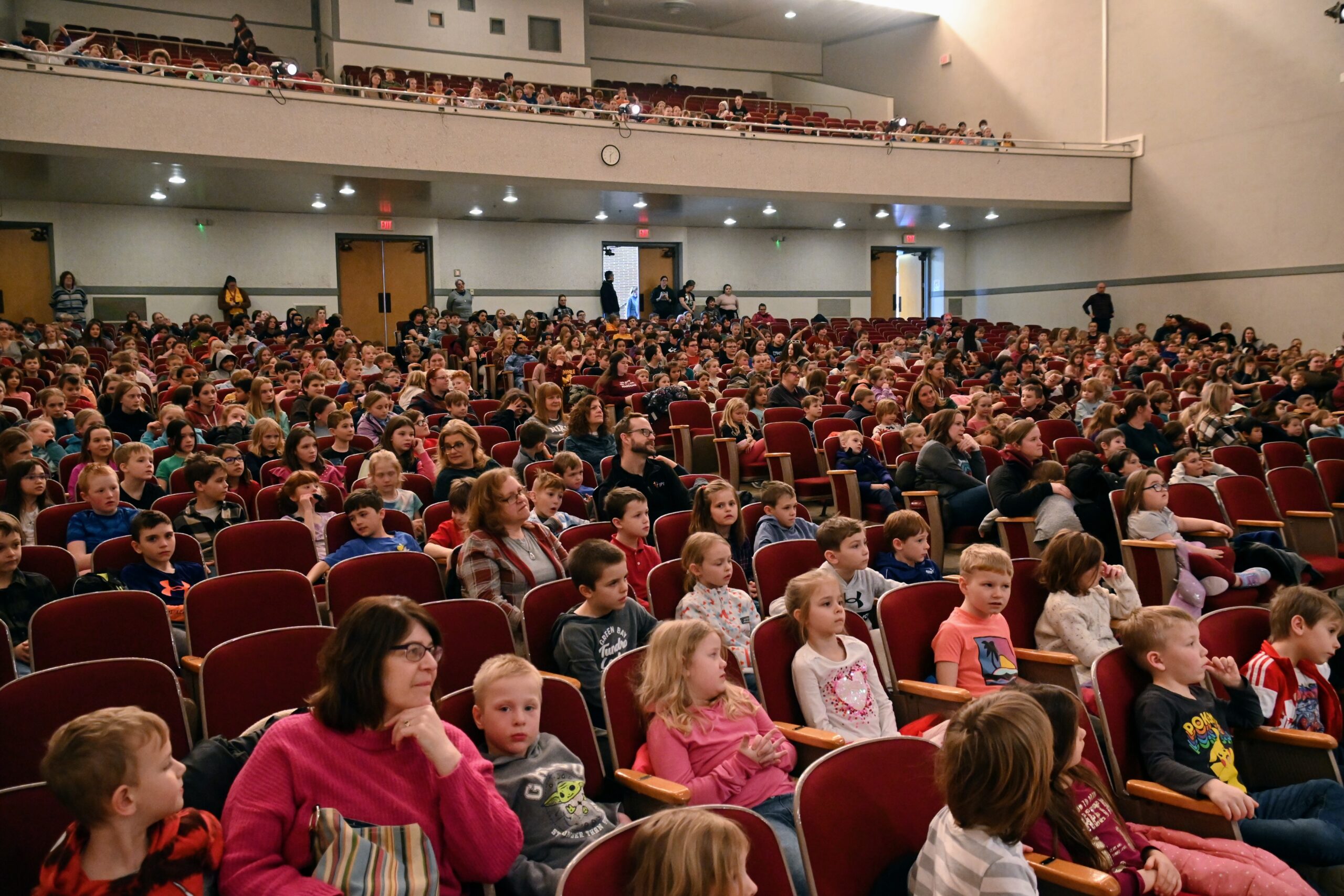 An theater full of engaged elementary school students watch a performance