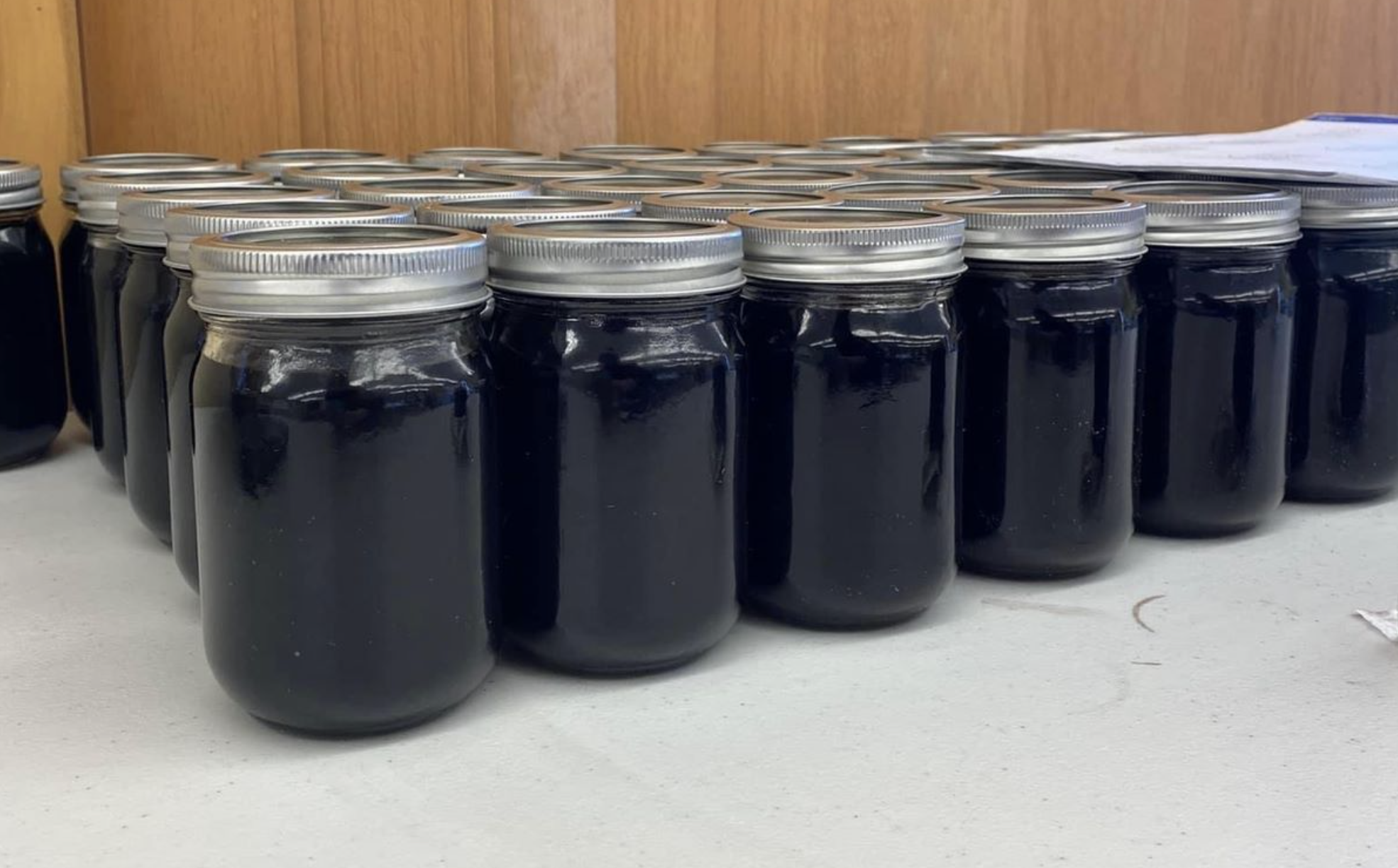 Many jars filled with liquid are lined up on a table.
