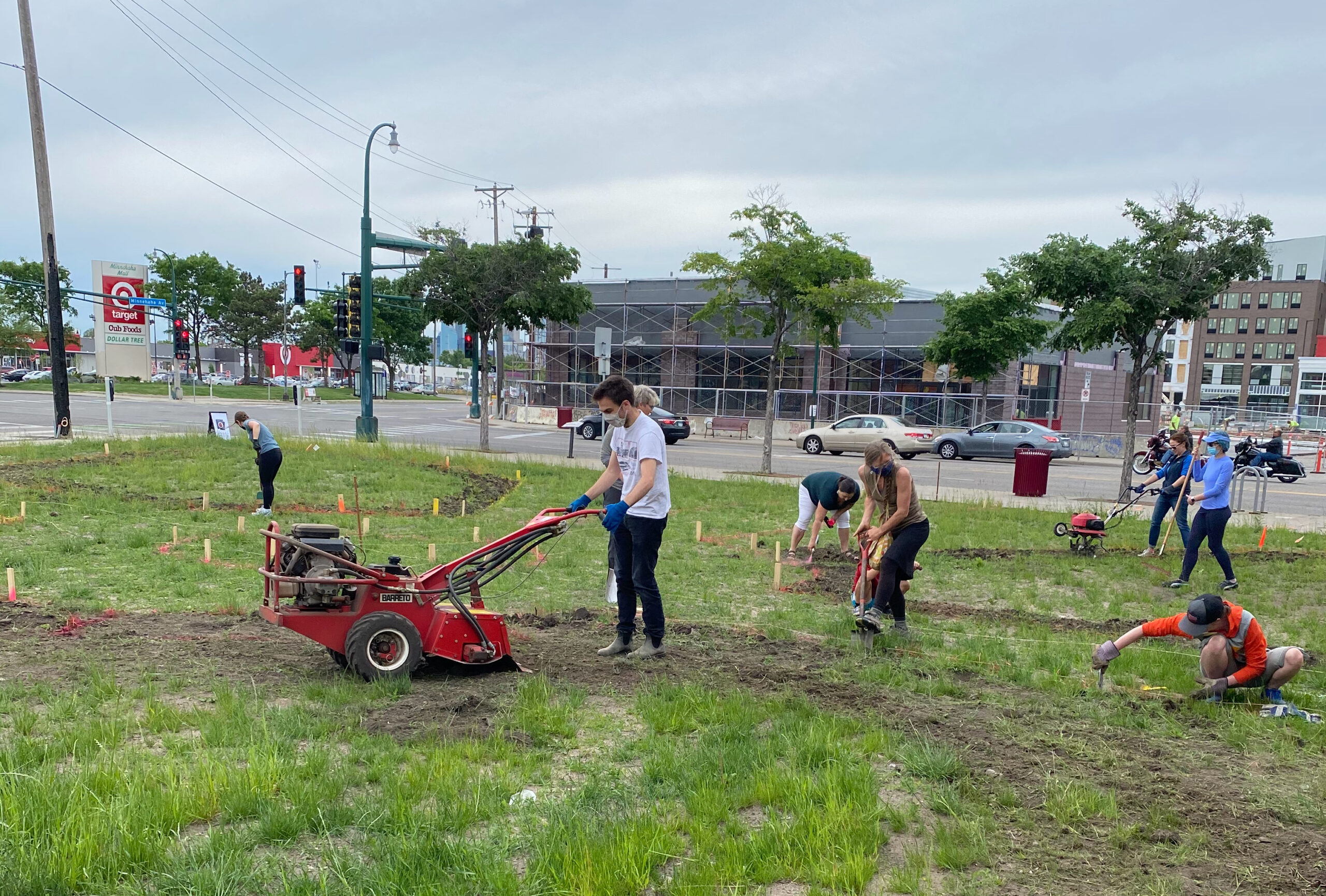Multiple people work together to till, dig and tend to the grass and dirt, on a patch of land near Lake Street in Minneapolis.