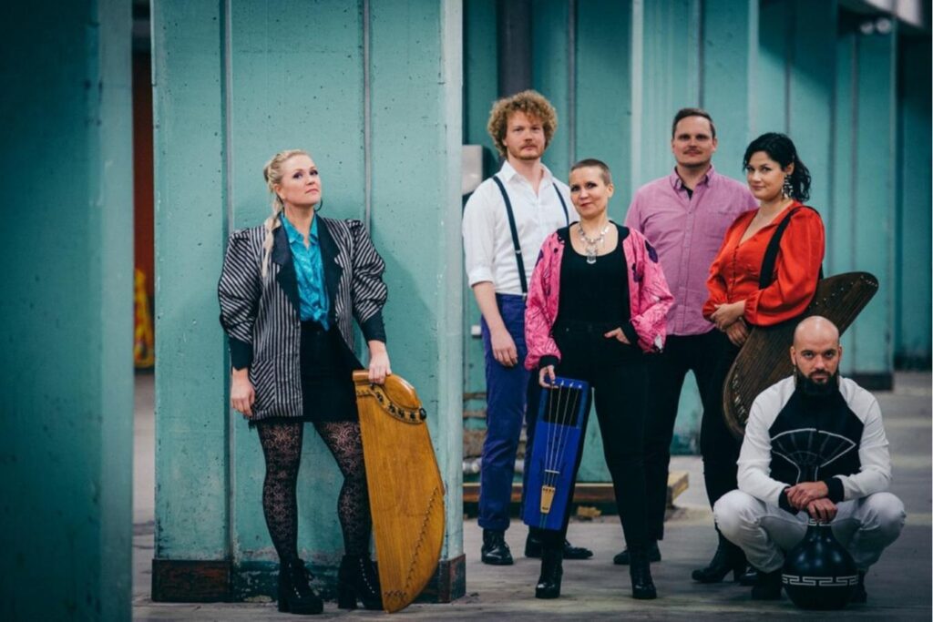 Finnish music group Okra Playground stand together for a photo, holding various instruments including a jouhikko.