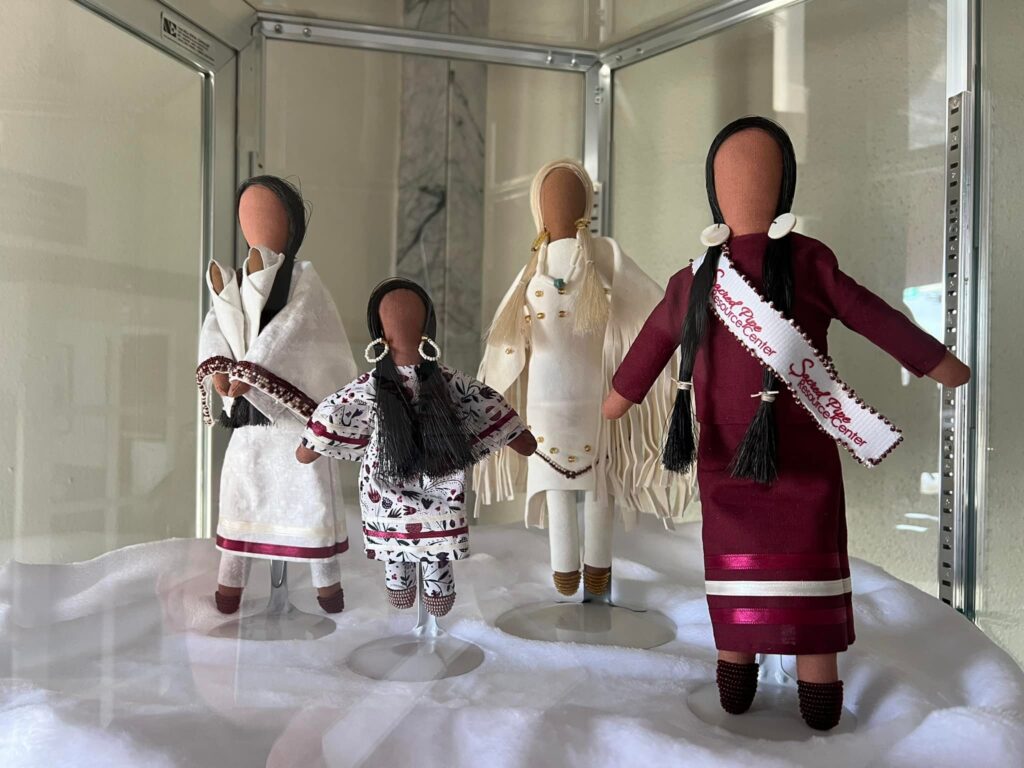 Dolls in a glass case at Sacred Pipe Resource Center.
