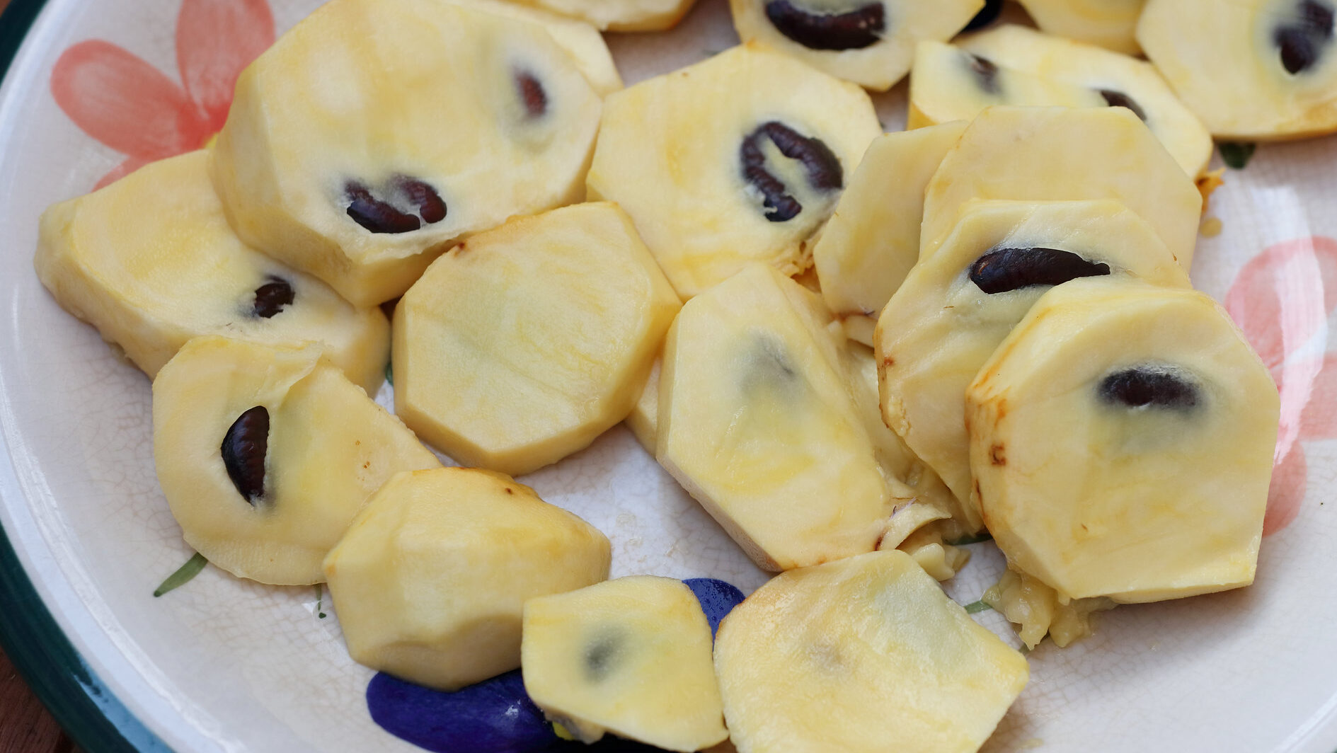 Sliced Pawpaw fruit on a floral patterned plate.