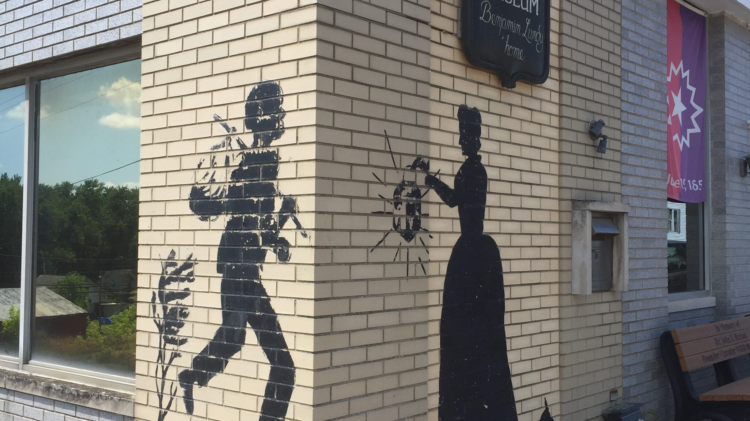 Painting on the outside of the Underground Railroad Museum in Flushing, Ohio. It depicts a person carrying a sack on a stick over their back, and another person holding a shining lantern.