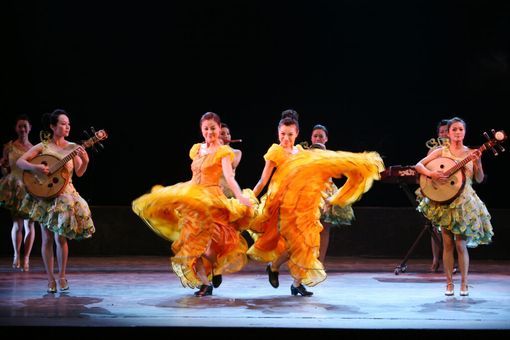 Beauty and Melody, an all-female ensemble from Sichuan Province in China, dance and play music on stage.