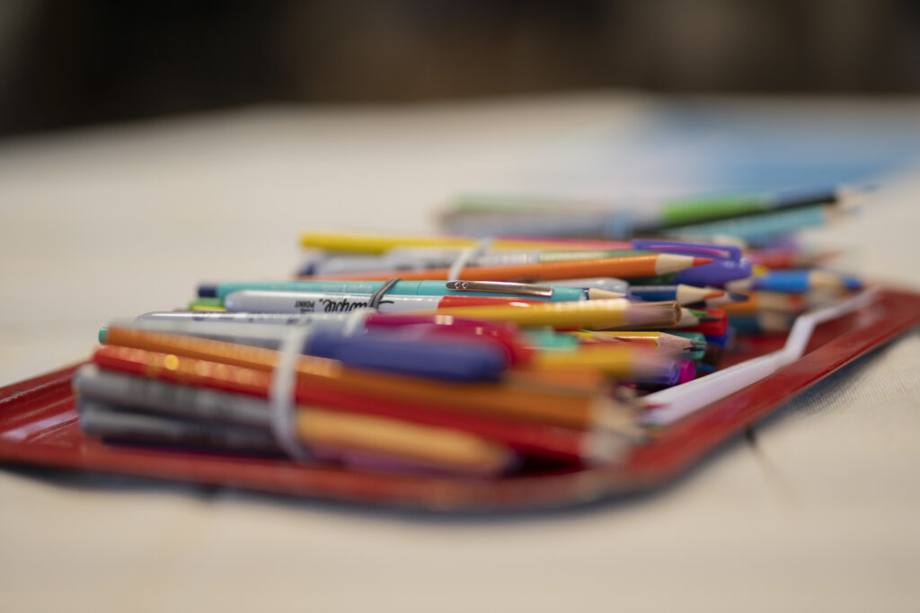 Close up of pens, pencils and markers grouped together in rubberbands.