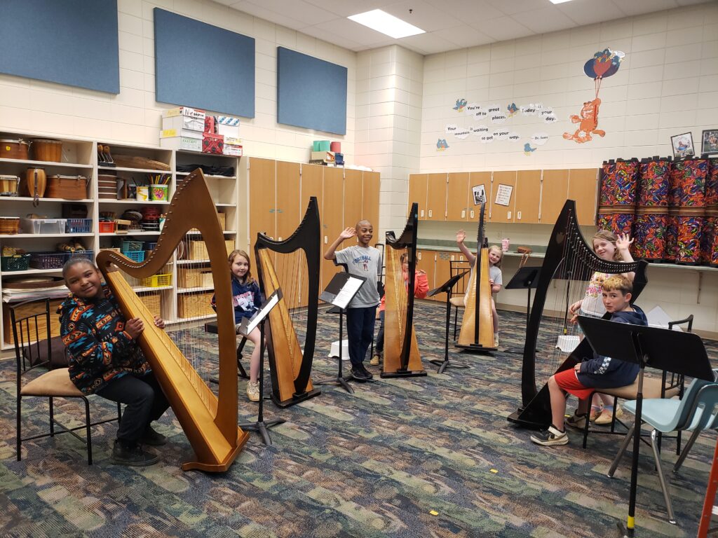 Children perform on harp instruments in a music room as part of Chamber Music Festival of the Black Hills.