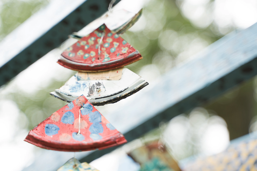 Close up of a hanging sculpture, consisting of multiple triangle shaped pieces painted in red, with polka dot patterns in blue, yellow and green.