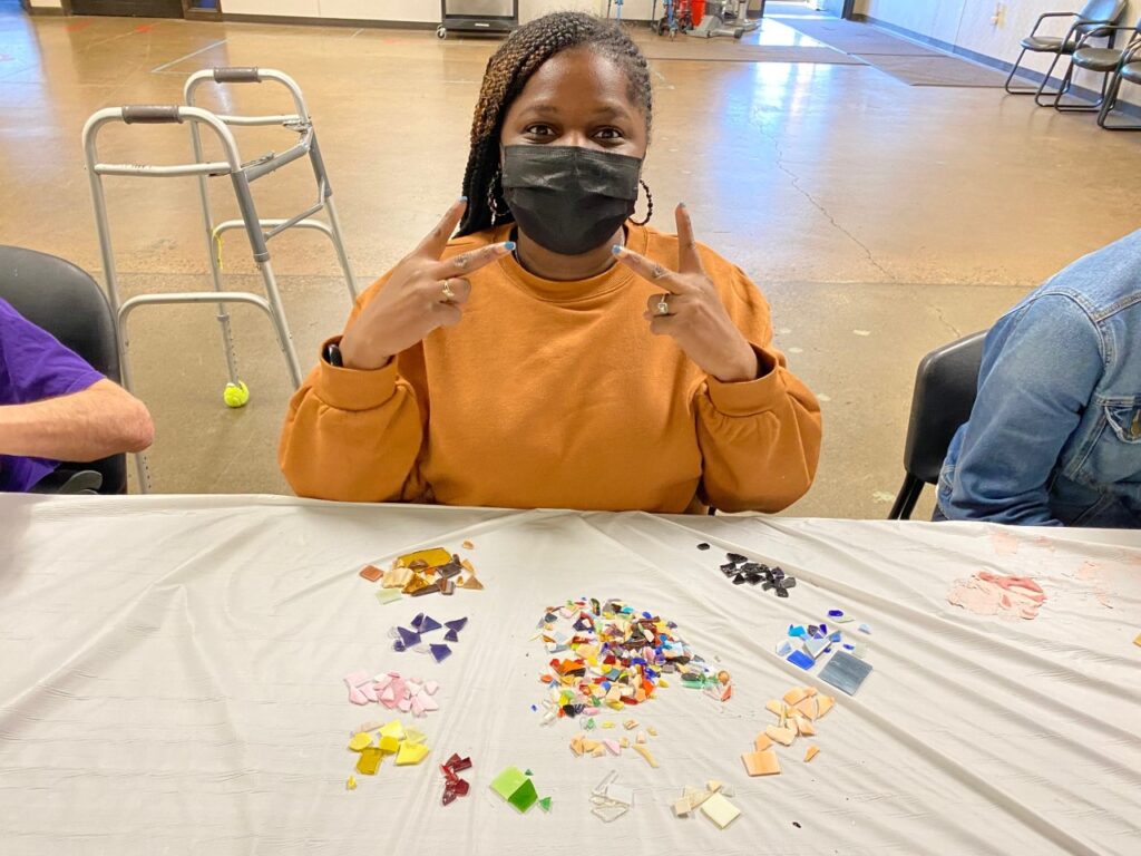 A person participating in an image glass sorting activity poses for the camera, holding up two peace signs.