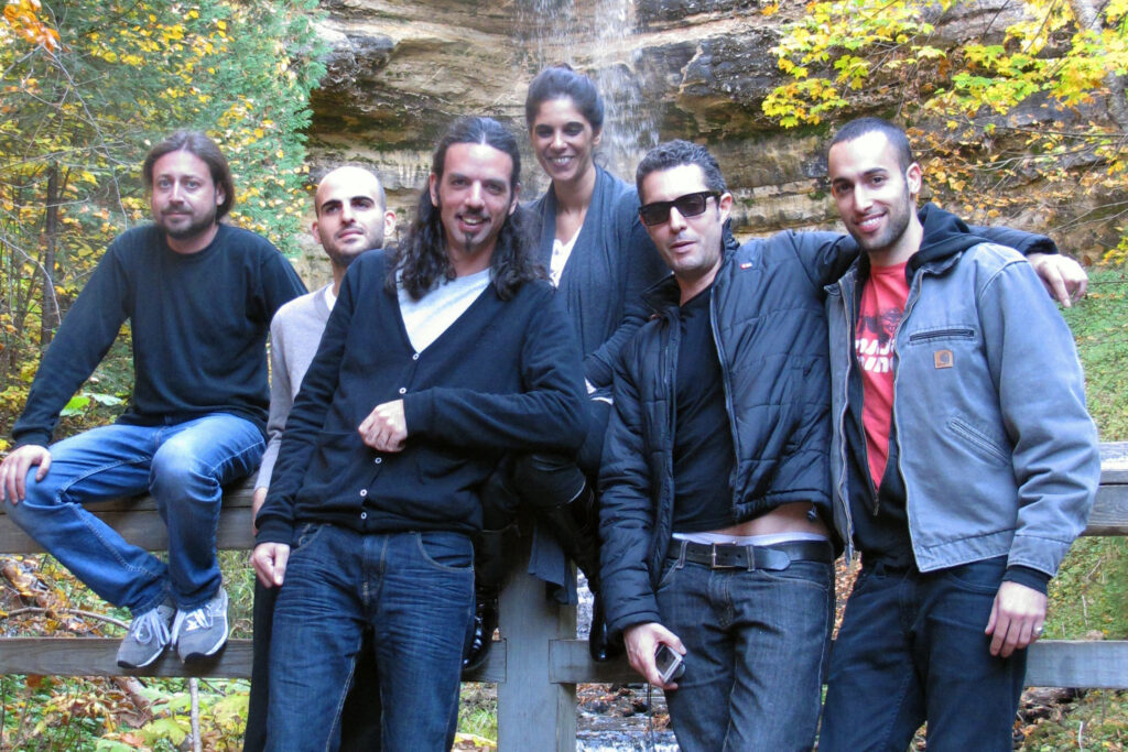 The Israeli Ethnic Ensemble, a band based in Israel, pose for a photo in front of a waterfall.