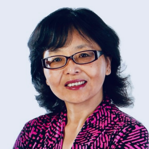 Headshot of a smiling person of medium light skin tone and shoulder length black hair, wearing dark framed glasses and red lipstick, and a patterned pink and black shirt.