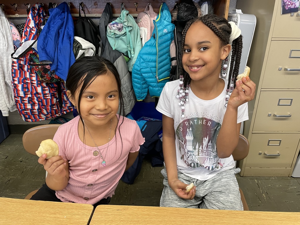 Two students are smiling and posing with fry bread.