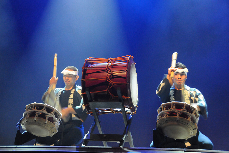 Ondekoza, a band based in Japan who masters in taiko drumming, perform on a stage cast in blue light.