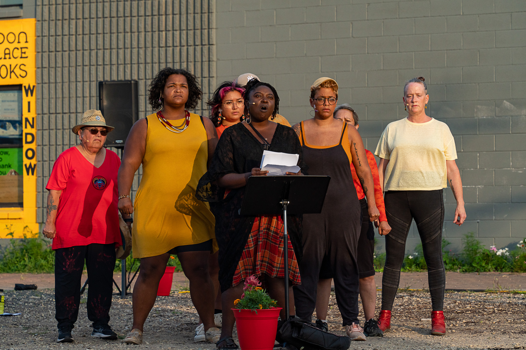 A group of ensemble members from Pangea World Theater’s “Life Born of Fire” performs in front of Moon Palace Books in Minneapolis. They look forward and pose in determined stances.