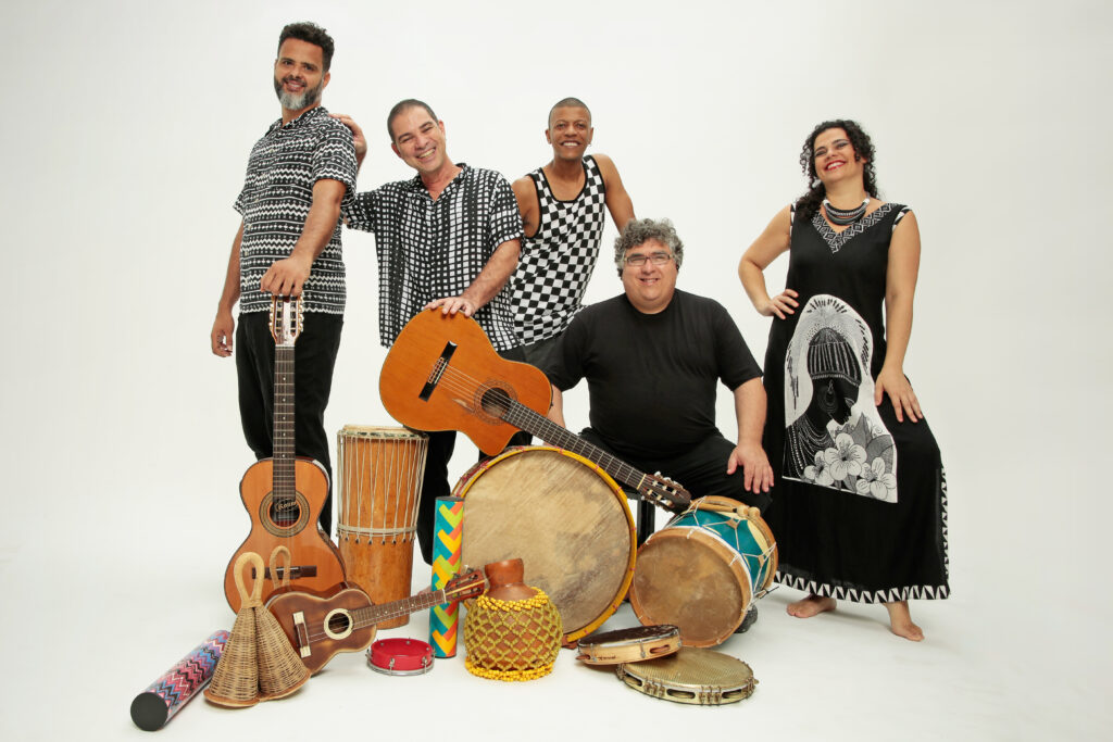 Paulo Padilha e Bando, a samba swing artist from Brazil, poses with his band and their instruments, including guitars and various types of drums.