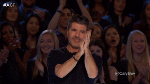 gif of Simon Cowell giving two thumbs up with an audience celebrating behind him