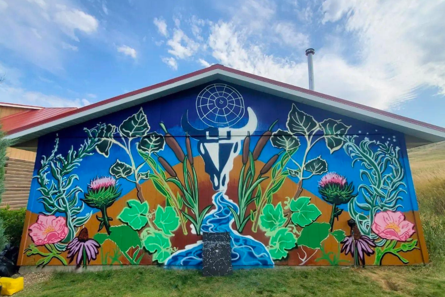 Mural at the Visitor Center, painted by Standing Rock artist Sunshine Claymore. It depicts vibrant plants and flowers, with a stream running through the center and a buffalo skull above.