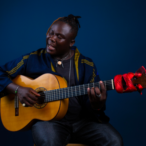Photo of a Ghanian man holding a guitar and singing