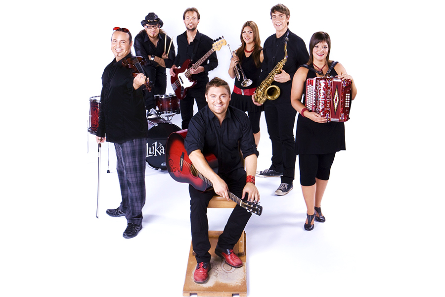 Mauvais Sort, a "folk 'n roll" band from Quebec, poses for a photo. They hold up their instruments including guitar, fiddle, accordion, saxophone, trumpet, and drums.