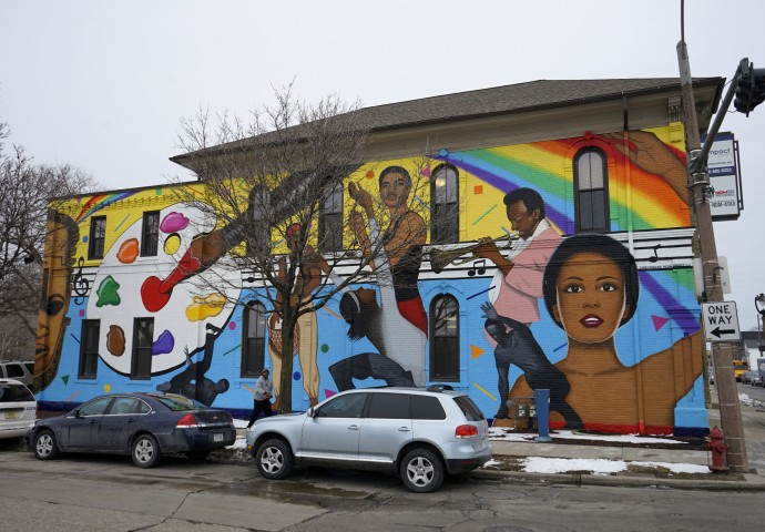 A colorful mural on the side of a Milwaukee building, featuring Black and brown visual artists and performers.
