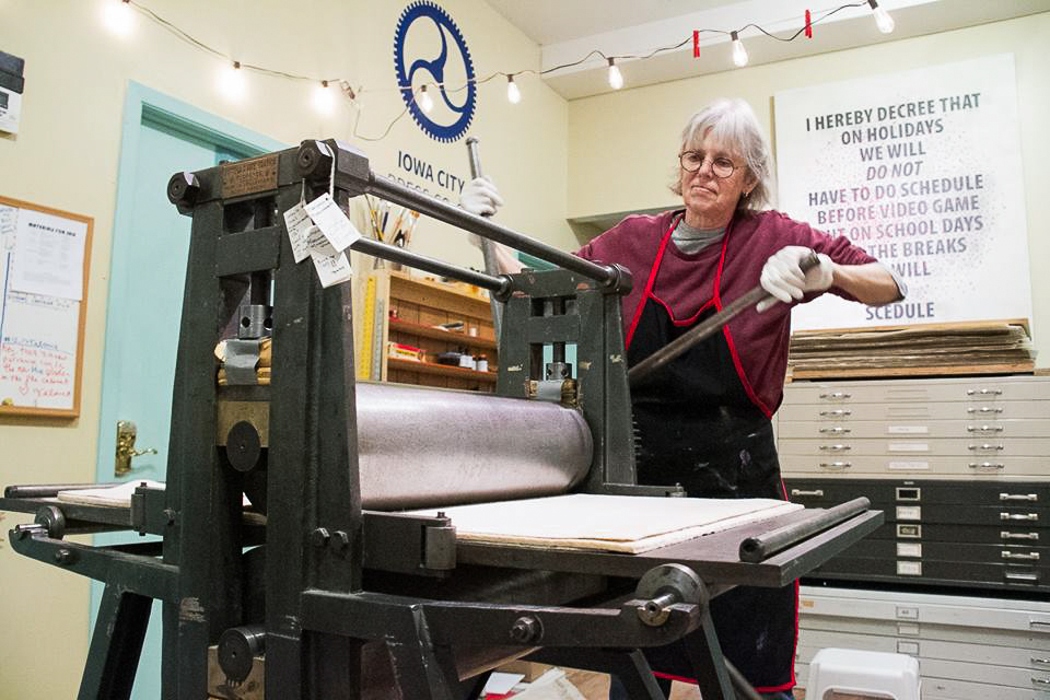 Iowa City Press Co-op member Martha Monick operates a printmaking press as they spin the handle in the community studio at Public Space One in Iowa City, Iowa, in 2016.