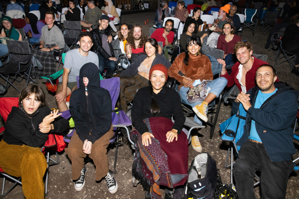 People smiling and pose for the camera as they sit in lawn chairs at the outdoor screening/dance party closing of Mizna's 2022 Arab Film Fest.
