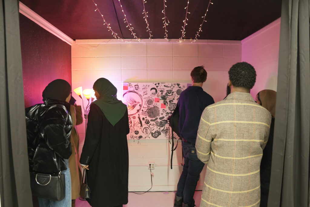 Visitors at Soomaal House participate in a writing and drawing prompt created by Aesha Mohamed as part of her exhibit, A Moon Shall Rise from My Darkness.