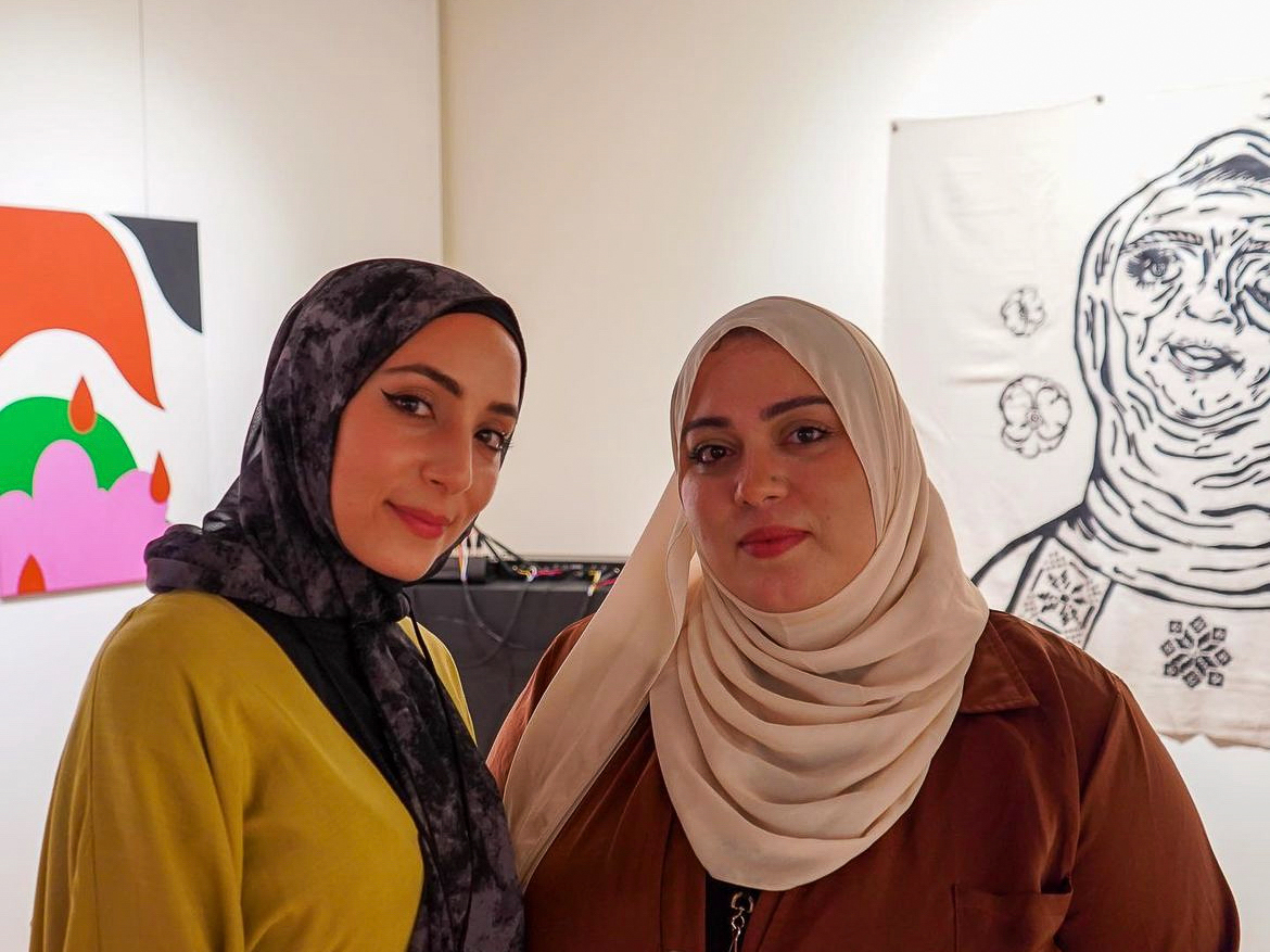 Founders of Fanana Banana, Amal Azzam (left) and Nayfa Naji, both wearing head scarves look at the camera and smile at an event they organized in Milwaukee, WI.