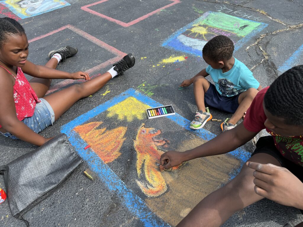 Three children make chalk art
