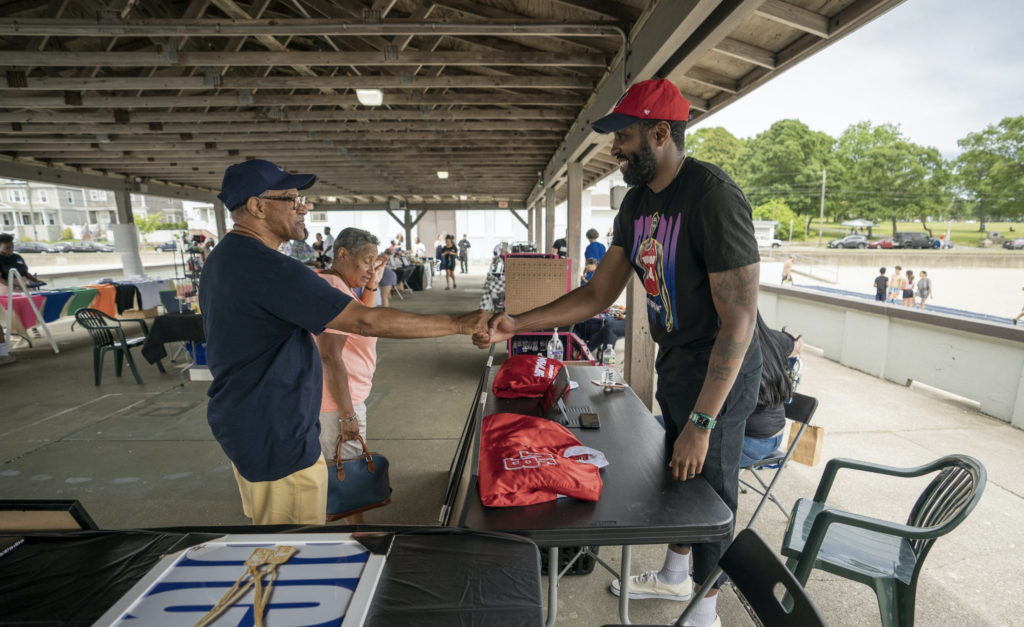 Two people shaking hands at an outdoor market.