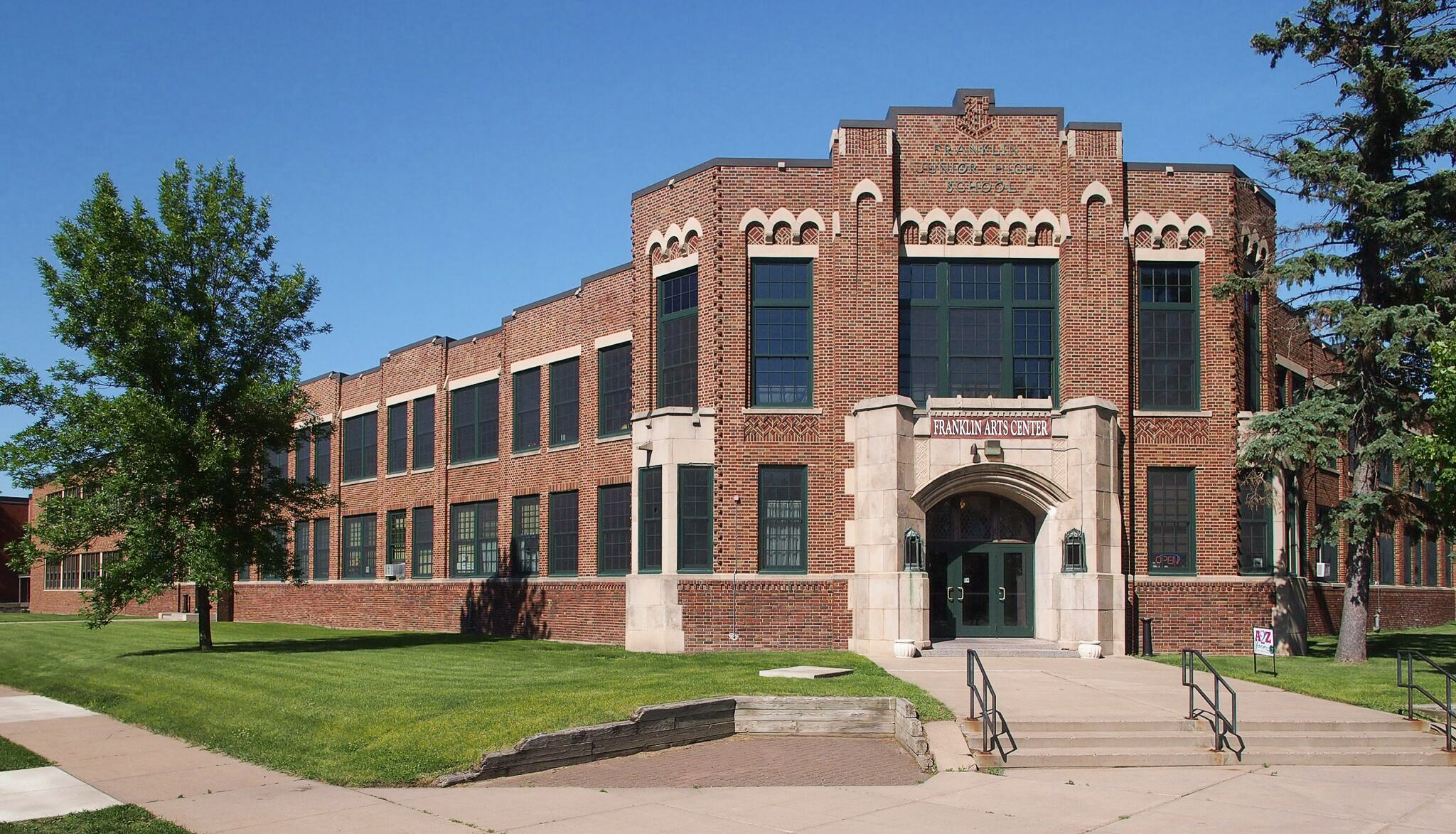 A large brown brick building with a banner on the front that reads "Franklin Arts Center"