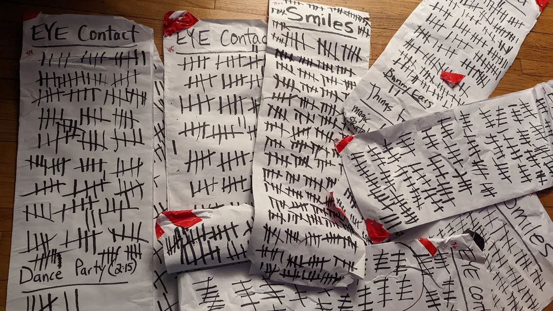 A pile of papers with tally marks that say smiles and eye contact at the top