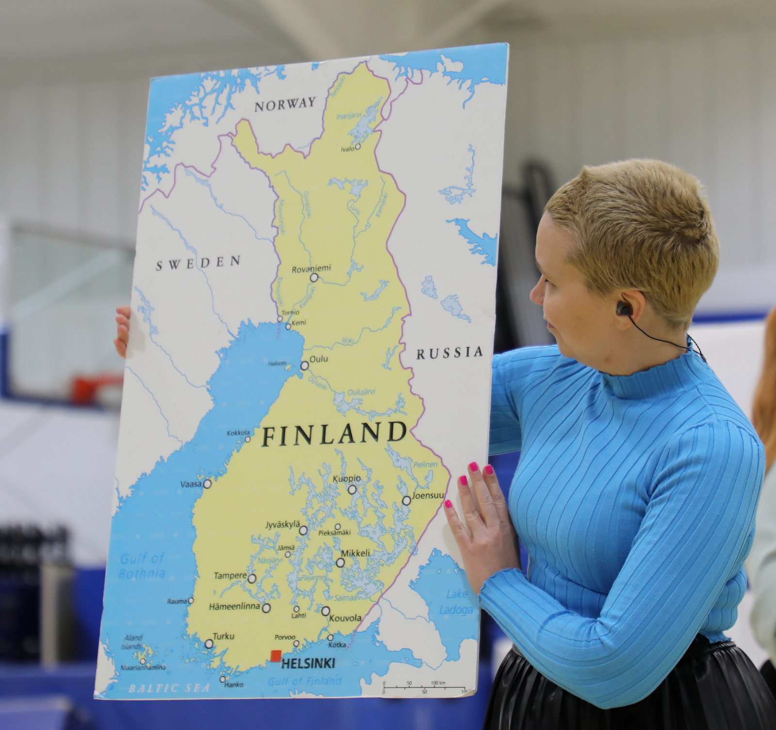 A woman holds up a large map of Finland