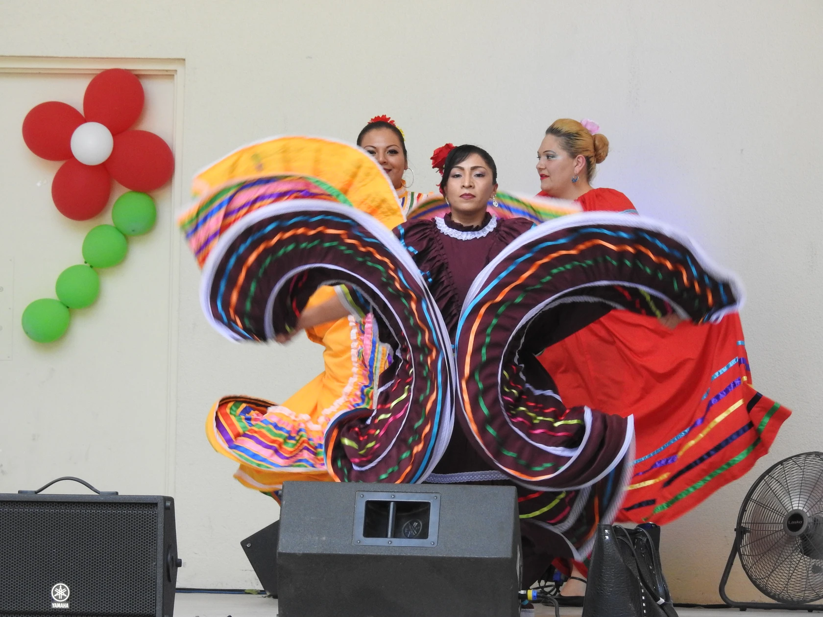A Mexican Folklorico dancer performs on stage twirling big colorful skirts