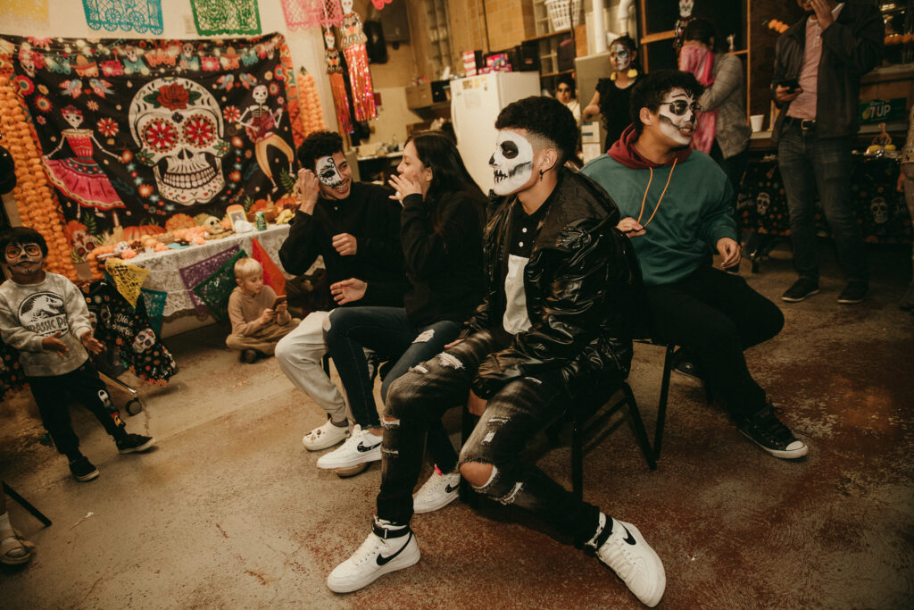 A group of teens in skull make up sit at a table