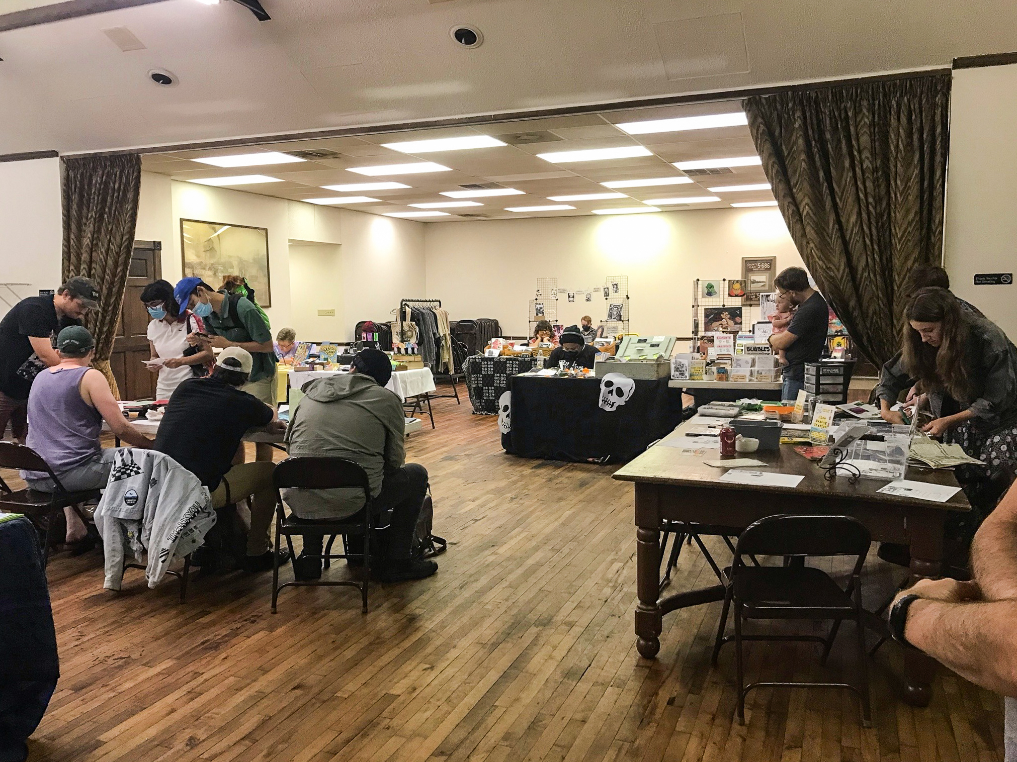 An indoor zine fest with many tables filled with papers