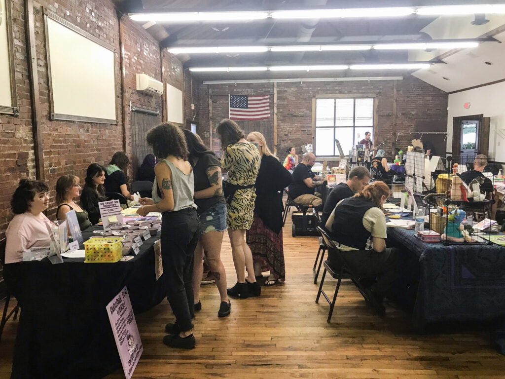 Attendees peruse tables filled with zines in a brick building