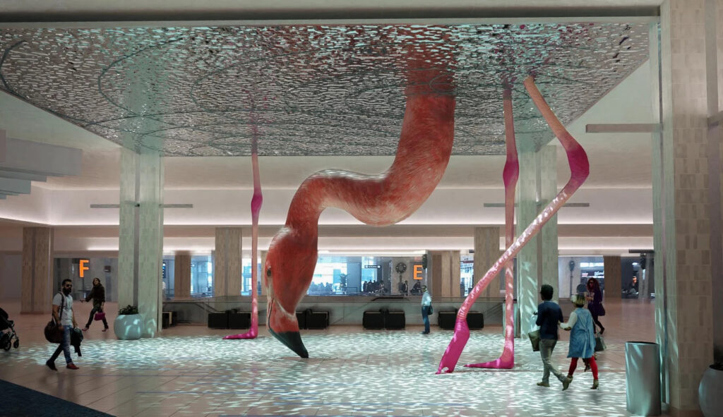 A public artwork located at an airport, depicting an oversized flamingo poking its head down to the ground from the ceiling.