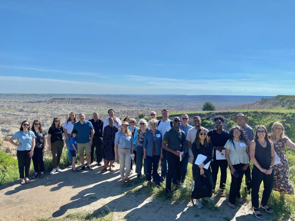 A large group of people pose in front of the Badlands of South Dakota.