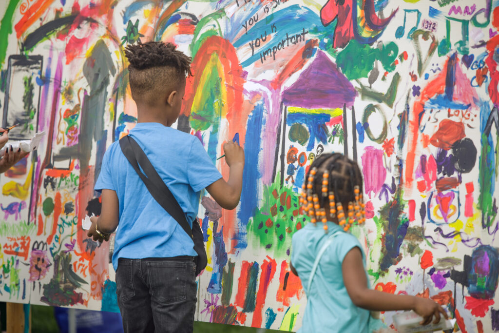 Two children paint on a colorful mural