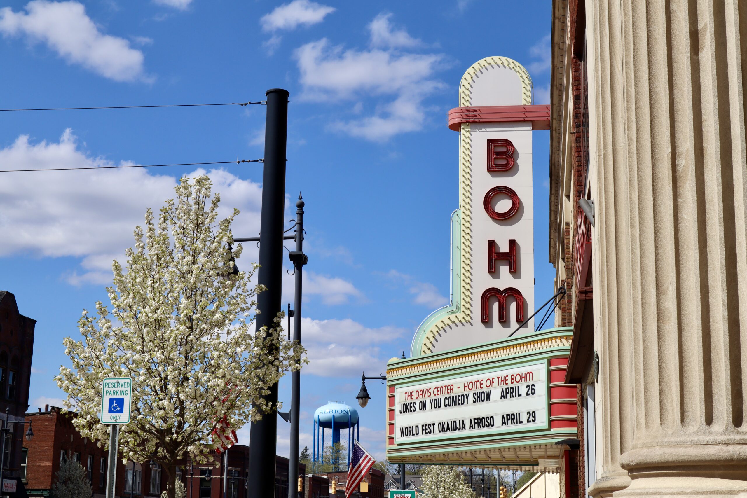A marquee of the Bohm Theatre in Albion, MI. A tree blooms in the background.
