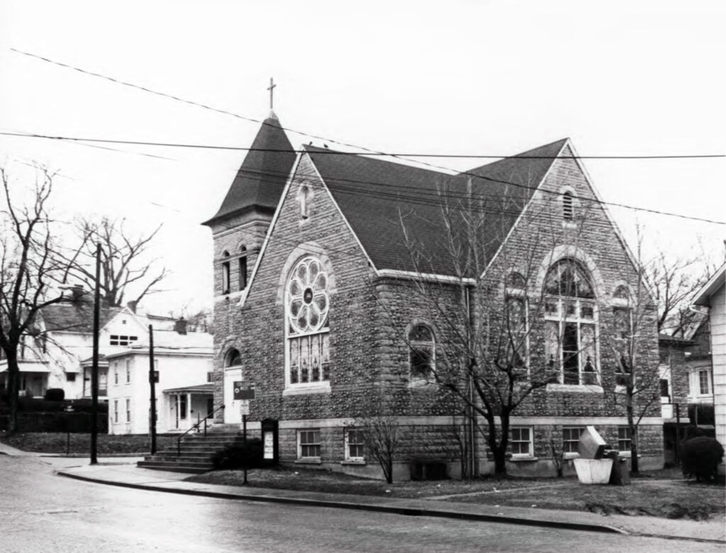 An archival black and white photo of a historic church with decorative stained glass windows.