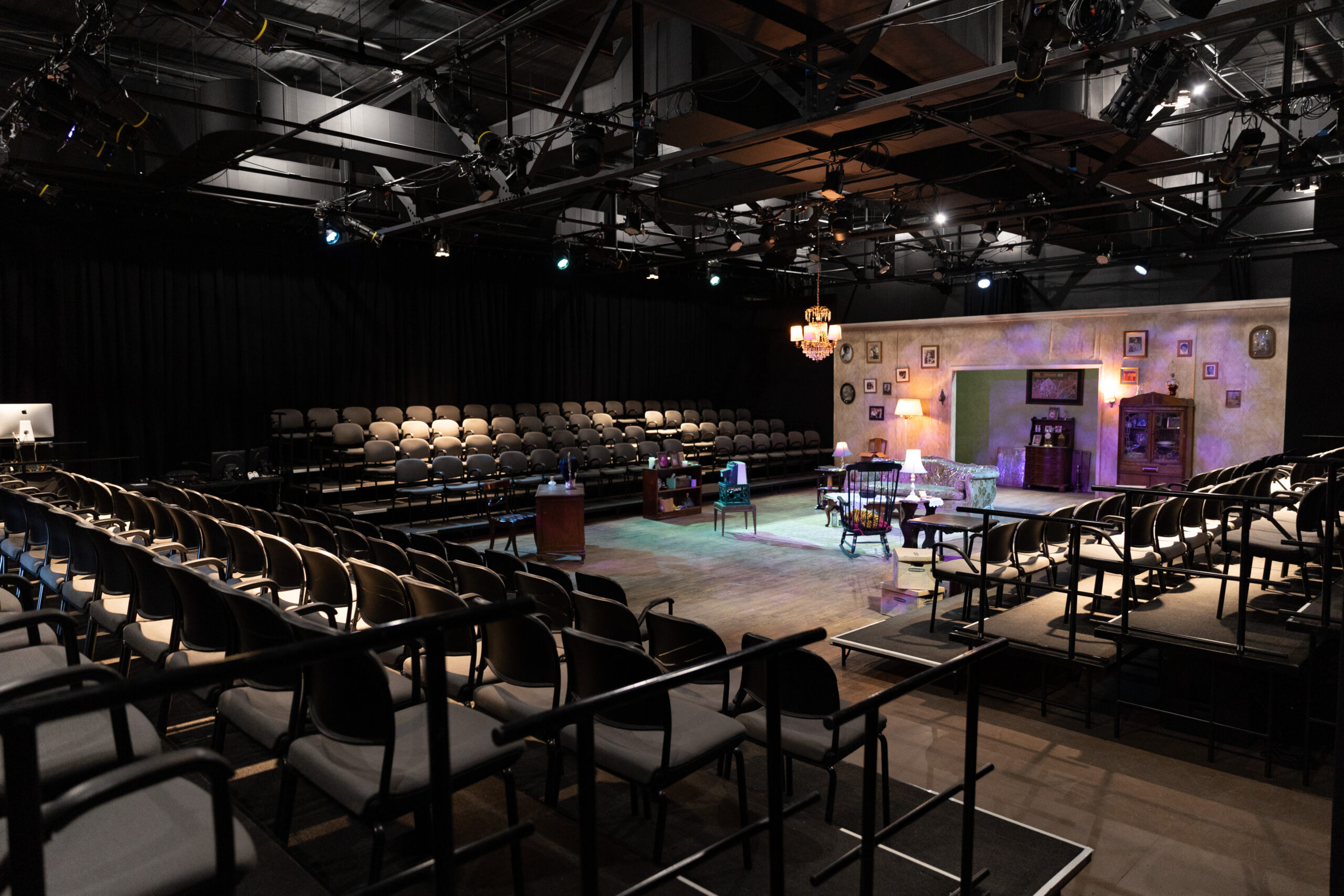 A wide look at a black box theatre with seats built on its three sides.