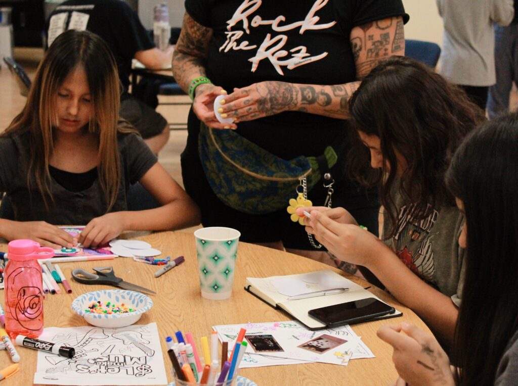 Two young people sit at a table, participating in an arts and crafts activity.