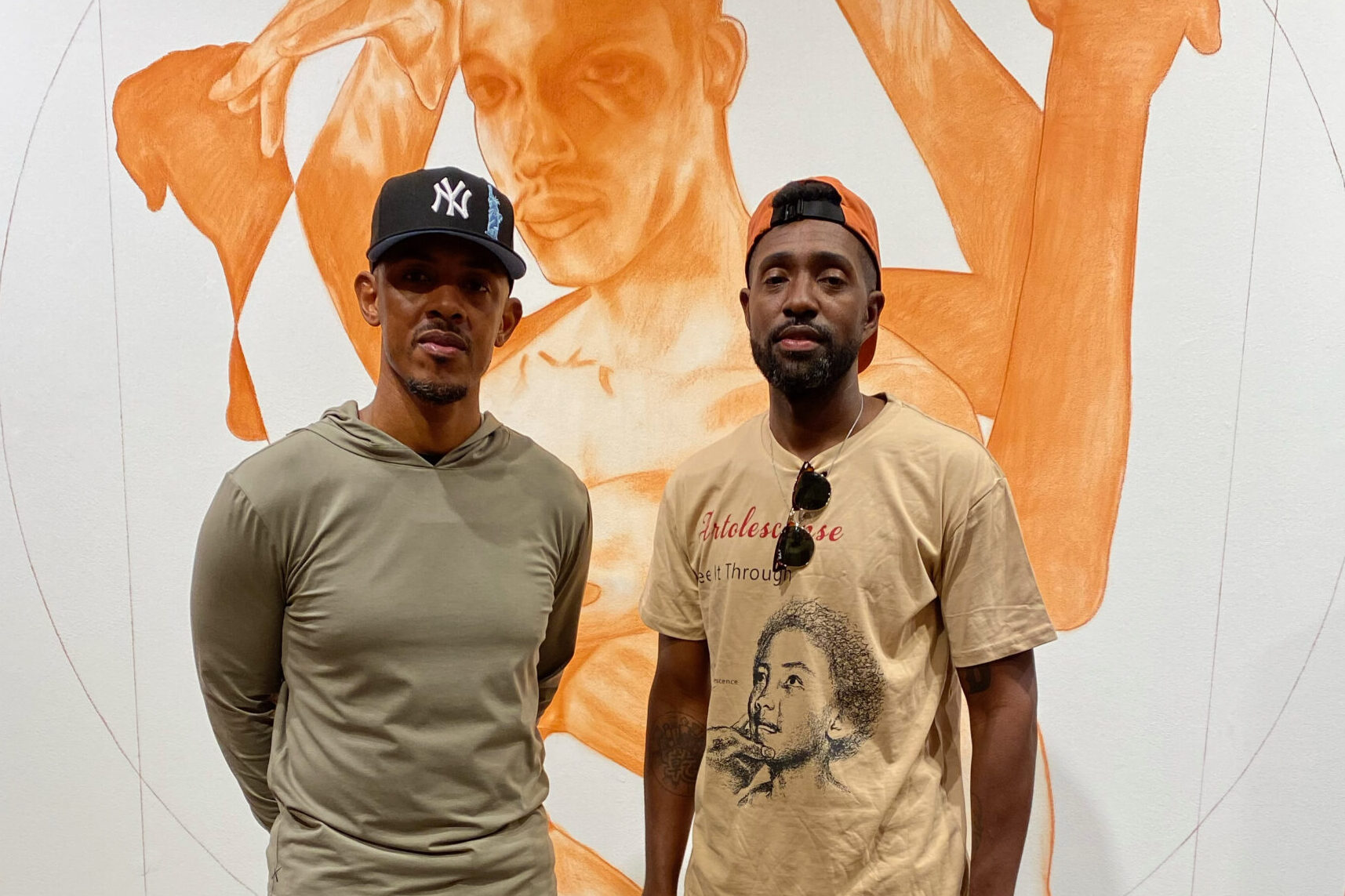 Two people of medium dark skin tone standing in front of a large painting.