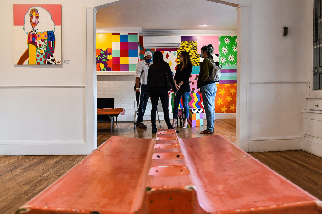 Four people in conversation in an art gallery with colorfully patterned walls.