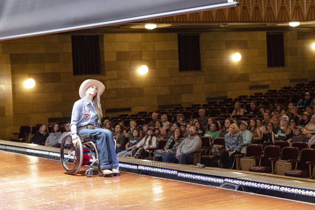 Woman in wheelchair on stage in theater.