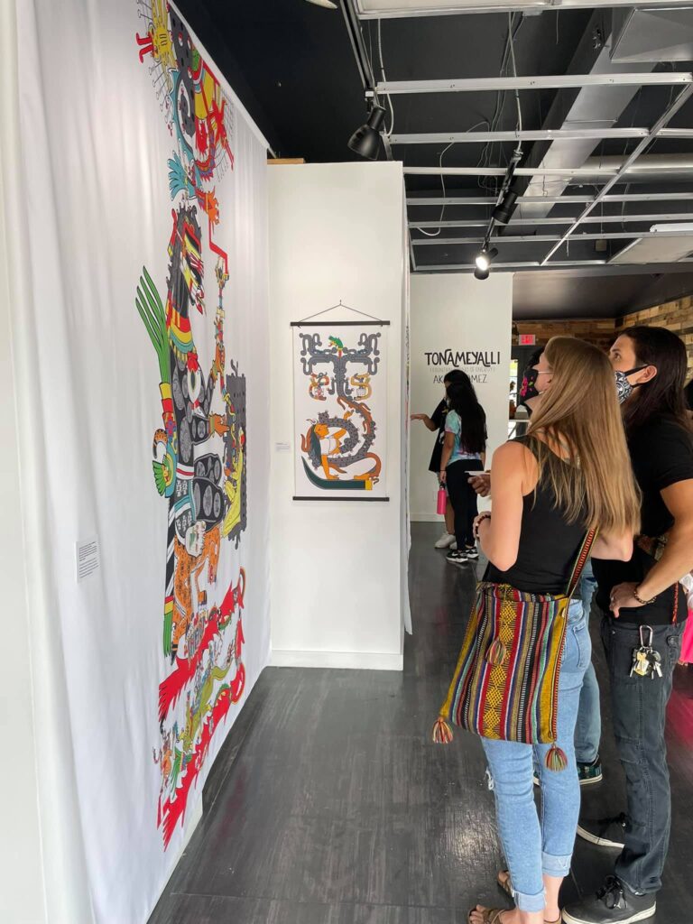 Two people stand in an art gallery and look at a colorful image printed on fabric.