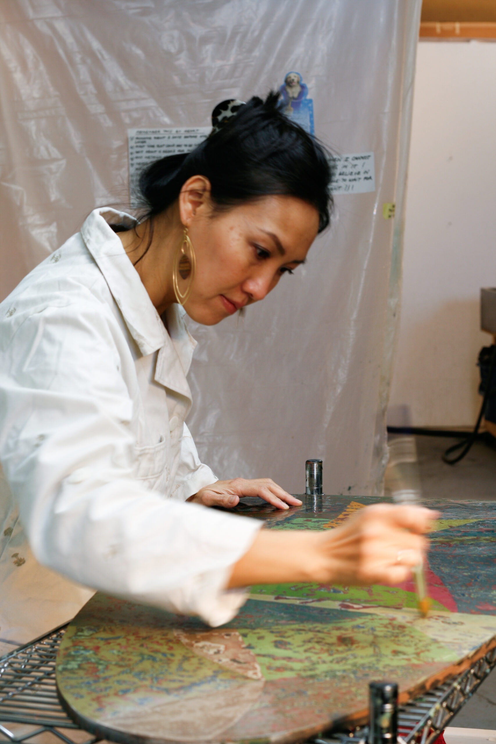 A person of light skin tone painting and working on a patterned surface.