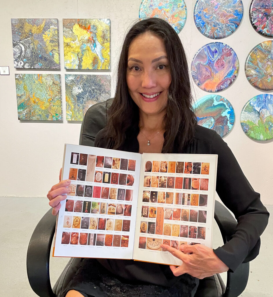 A person with long, dark hair, holds a book displaying thumbnails of images.